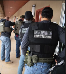 U.S. Marshals Fugitive Task Force officers in tactical gear during a fugitive arrest operation